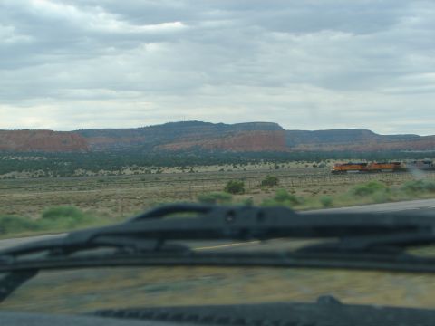 1992 Ford Taurus - A train travels through a desert landscape under a cloudy sky, with red rock formations visible in the distance.