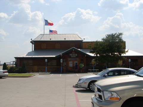 1992 Ford Taurus - A silver sedan is parked in the lot of a Texas Roadhouse restaurant under a cloudy sky.