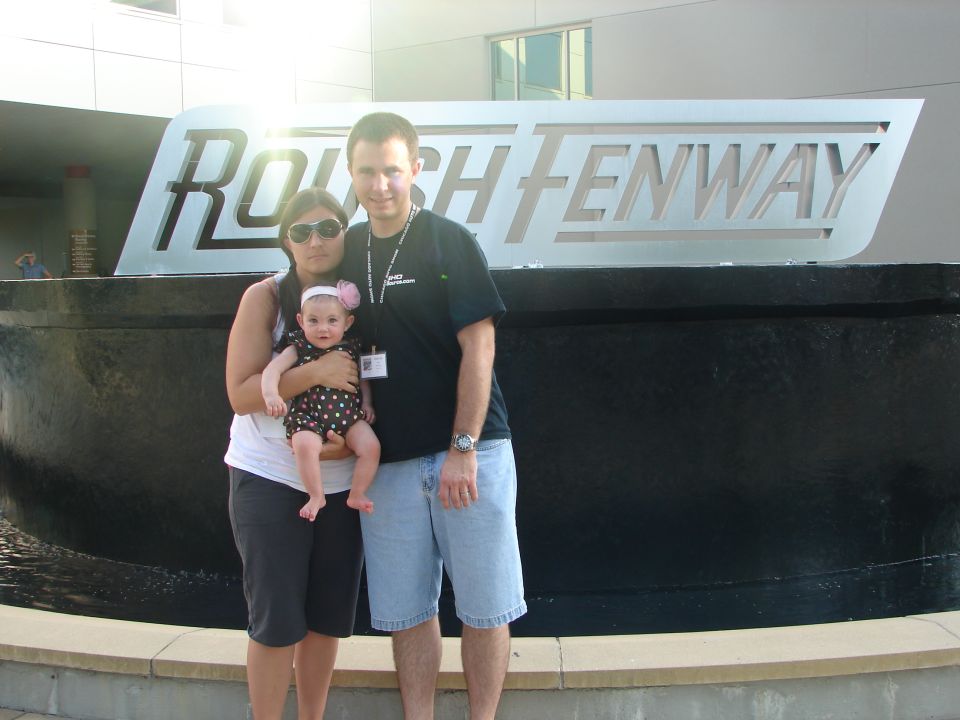 Family poses in front of the ROUSH FENWAY sign
