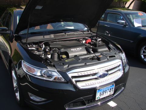 1992 Ford Taurus - Black Ford Taurus SHO with hood open, revealing the engine and front grille. Another car is visible to the right.