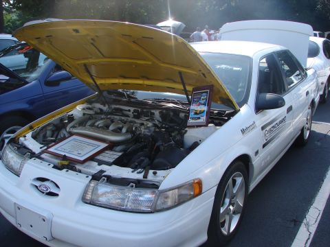 1992 Ford Taurus - A white 1992 Ford Taurus is displayed with its hood open, revealing the engine and a plaque with vehicle information.