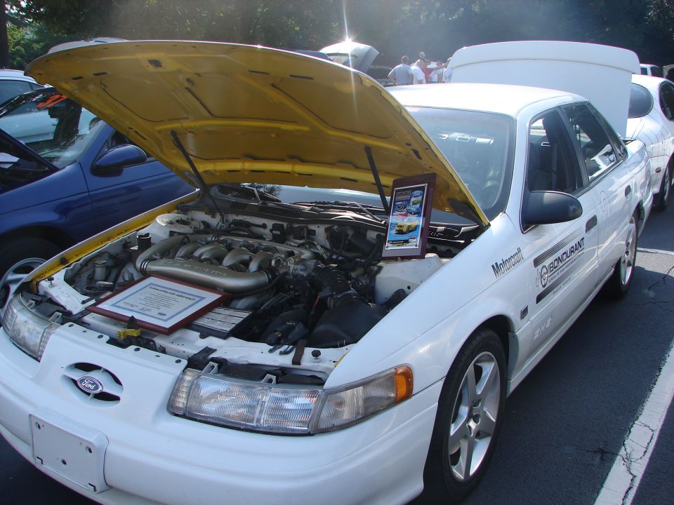 White 1992 Ford Taurus with hood open, showing engine and display plaque