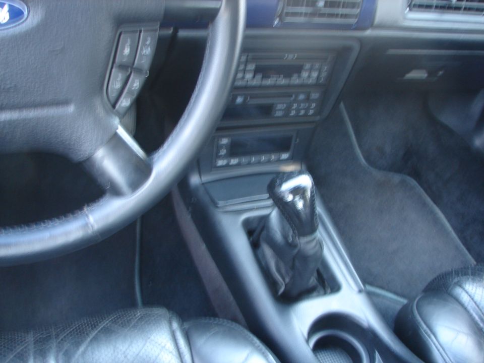 Interior of a 1992 Ford Taurus showing the steering wheel, dashboard, center console with gear shifter, and part of the driver's seat