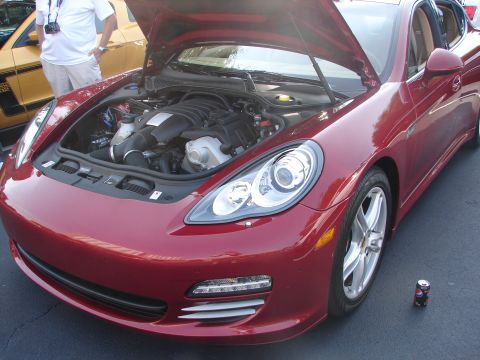1992 Ford Taurus - Red Porsche Panamera's engine bay is exposed, with a yellow Ford Mustang partially visible behind it.