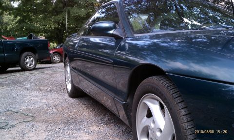 1997 Ford Probe - A dark green coupe is parked on a gravel surface, with other vehicles visible in the background.