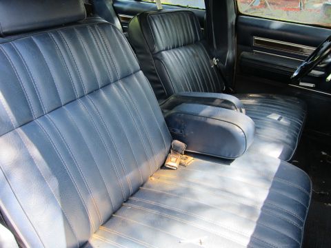 1991 Ford LTD Crown Victoria - The interior of a vehicle features blue vinyl bench seats with a center armrest and visible seatbelts.