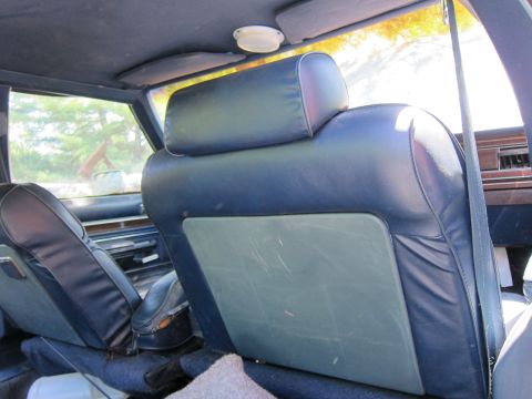 1991 Ford LTD Crown Victoria - The interior of the vehicle shows worn blue seats and a view through the window.