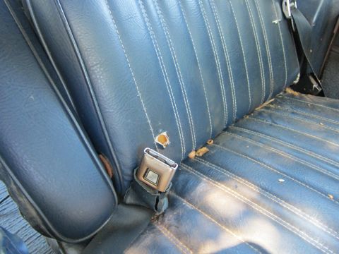 1991 Ford LTD Crown Victoria - Close-up of a worn blue car seat with a visible seatbelt buckle and debris on the surface.
