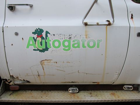 1991 Ford LTD Crown Victoria - Side view of a white truck door an 'Autogator' sticker and signs of rust.