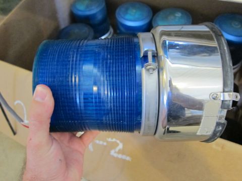 1991 Ford LTD Crown Victoria - A blue strobe light is held in a hand, with other similar lights visible in a box.