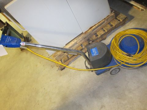 1991 Ford LTD Crown Victoria - A blue floor buffer machine with a coiled yellow power cord rests on a concrete floor next to a wooden pallet.