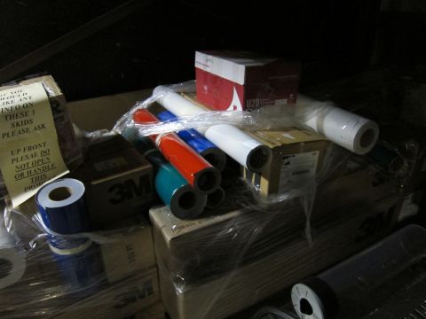1991 Ford LTD Crown Victoria - Various rolls of colored vinyl are stacked on boxes, some with 3M branding, in a storage area.