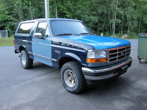 2001 Ford Crown Victoria - Two-tone blue Ford Bronco parked on asphalt with trees in the background.