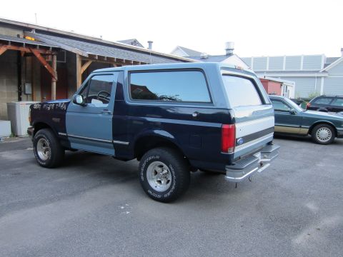 2001 Ford Crown Victoria - A two-tone Ford Bronco is parked in a lot with another car visible in the background.