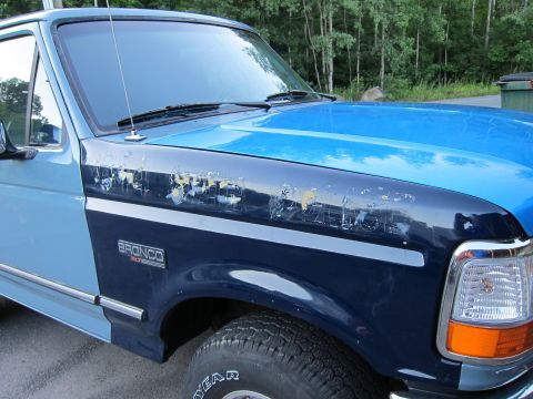 2001 Ford Crown Victoria - This two-tone blue Ford Bronco shows significant paint wear on the hood and fender, with the "Bronco XLT" badge clearly visible.