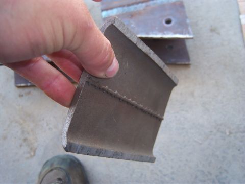 1996 Ford Bronco - A metal bracket is held up for inspection, with other metal pieces in the background.