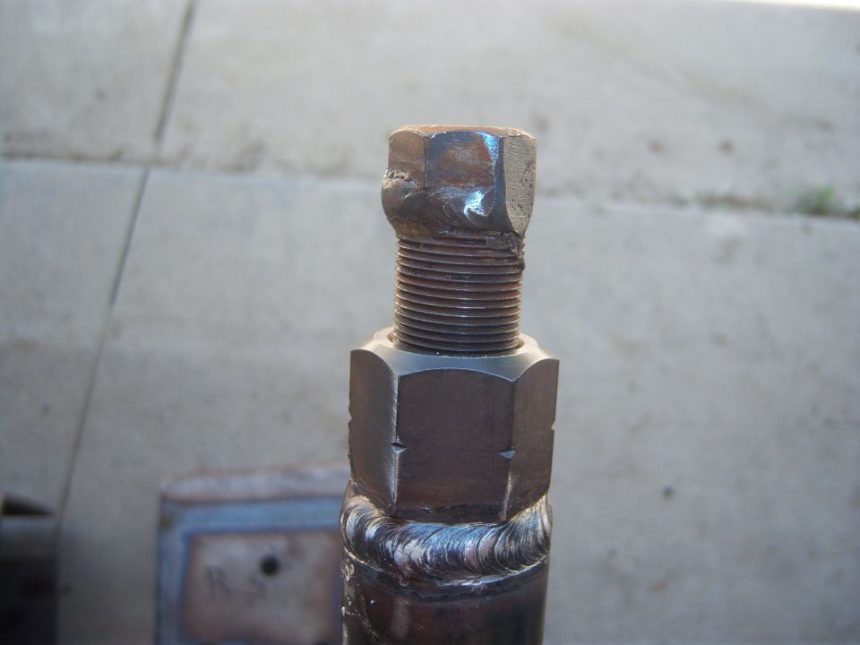 Close-up of a metal rod with a nut and bolt welded onto it