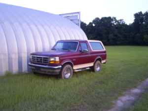 1992 Ford Bronco - This 1992 Ford Bronco is parked outside a large building with trees in the background.