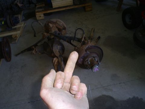 1992 Ford Bronco - Two rusty front axle assemblies are shown, with a hand obscuring part of the view and giving the middle finger.