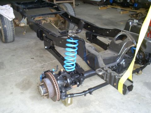 1992 Ford Bronco - The chassis of a 1992 Ford Bronco is shown with its front suspension components, including bright blue coil springs.