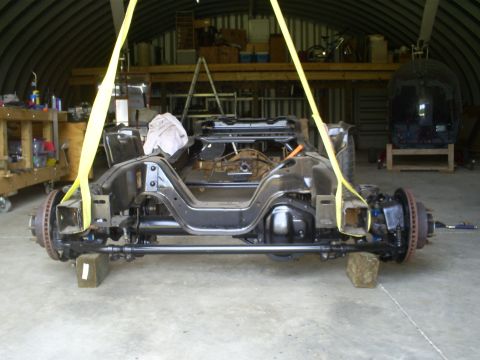 1992 Ford Bronco - Vehicle frame and suspension assembly is being lifted in a workshop.