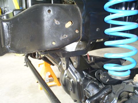 1992 Ford Bronco - The image shows a close-up of a vehicle's suspension system, including a bright blue coil spring and various metal components.