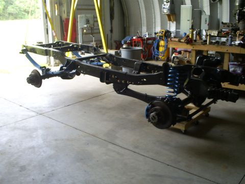 1992 Ford Bronco - The chassis and suspension components of a vehicle are displayed in a workshop setting.