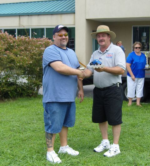 2007 Ford Mustang - Two men shake hands at an outdoor event, with one man holding a small toy car trophy.
