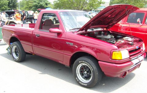 2007 Ford Mustang - A red Ford Ranger pickup truck is displayed with its hood open at an outdoor car show.