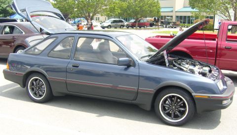 2007 Ford Mustang - A blue hatchback is displayed with its hood open, revealing the engine compartment. Another vehicle is parked behind it.