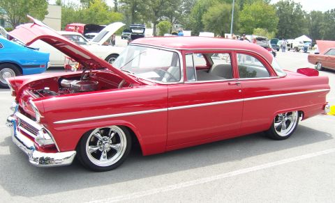 2007 Ford Mustang - A red 1955 Ford Fairlane sedan is displayed with its hood open at a car show.