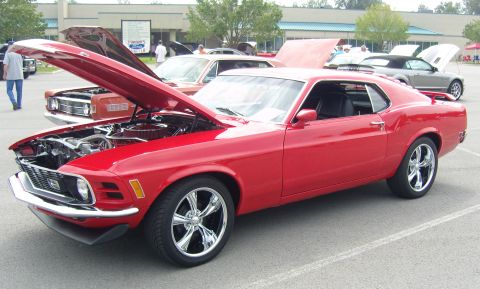 2007 Ford Mustang - A classic red Ford Mustang is displayed with its hood open at an outdoor car show.