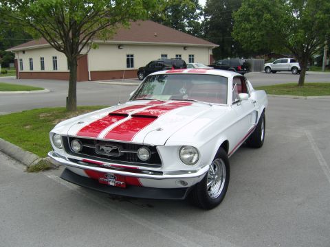 2007 Ford Mustang - A white 1967 Ford Mustang with red racing stripes is parked in a lot.