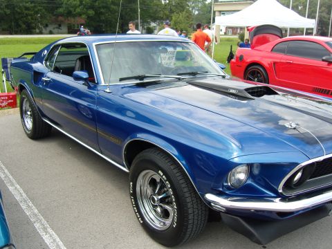 2007 Ford Mustang - A blue 1969 Ford Mustang Mach 1 is parked next to a red Mustang at a car show.