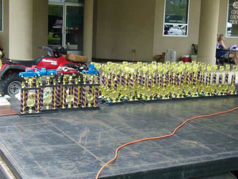 2007 Ford Mustang - A large collection of trophies is displayed outdoors, with an ATV and toy vehicles nearby.