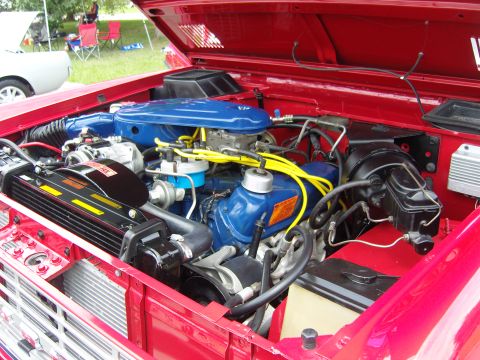 2007 Ford Mustang - Close-up of a red vehicle's engine bay, showing a blue Ford engine and associated components.