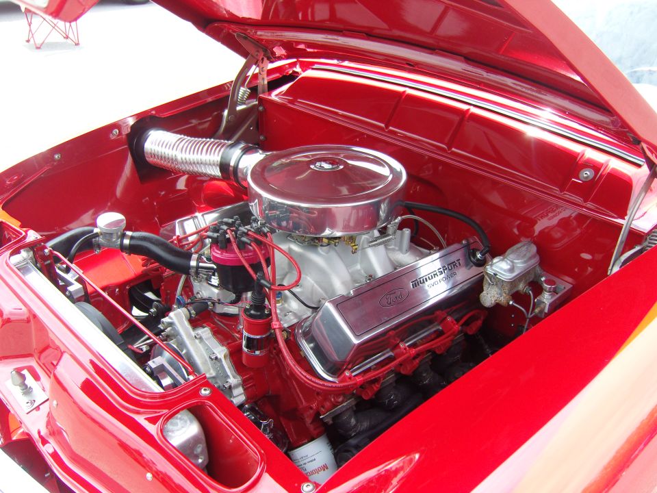 Close-up of a red Ford V8 engine with chrome details and "Motorsport" valve covers