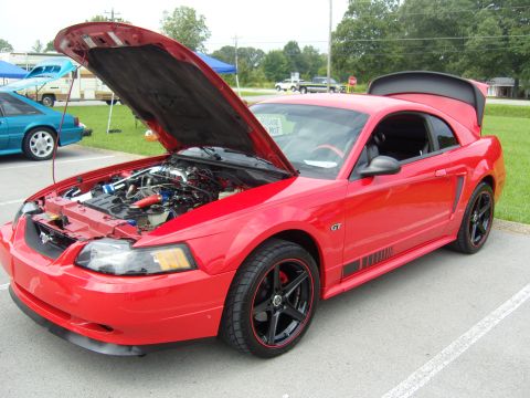 2007 Ford Mustang - A red Ford Mustang GT is parked with its hood and trunk open, revealing the engine and interior.