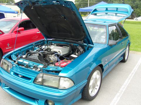 2007 Ford Mustang - Teal Ford Mustang hatchback at a car show, hood and trunk open, with another Mustang behind it.