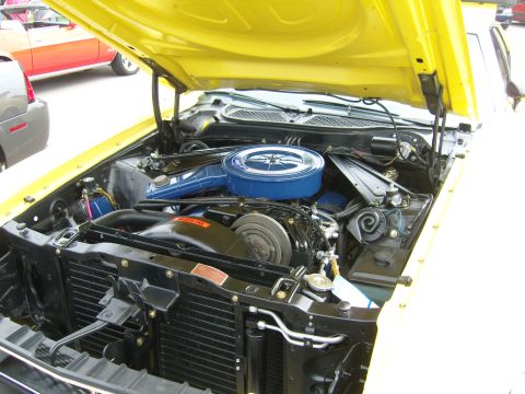 2007 Ford Mustang - The engine bay of a yellow classic car, likely a Ford Mustang from the early 1970s, is shown with other vehicles in the background.