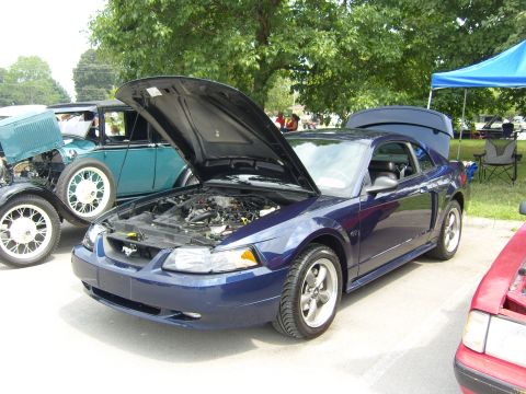 2007 Ford Mustang - A blue Ford Mustang is displayed with its hood open, alongside other vehicles at an outdoor car show.