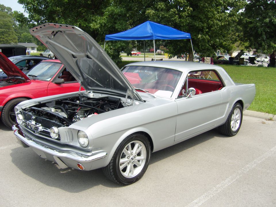 Silver 1965 Ford Mustang coupe with hood open, red interior, parked next to a red car
