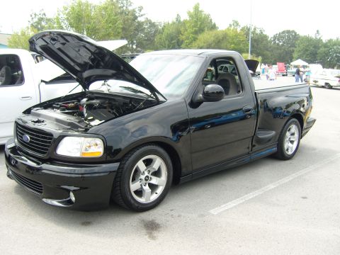 2007 Ford Mustang - Black Ford F-150 SVT Lightning pickup truck with its hood open, parked at an outdoor event.