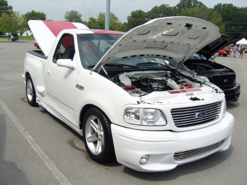 2007 Ford Mustang - White 2000 Ford F-150 SVT Lightning pickup truck with hood open and red racing stripes.