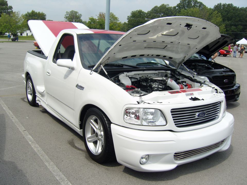 White 2000 Ford F-150 SVT Lightning pickup truck, hood open showing engine, red stripes on roof