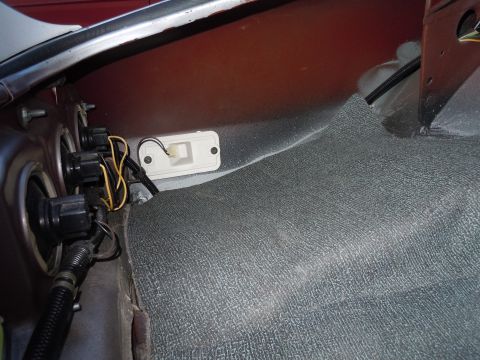 1976 Pontiac Trans Am - Close-up of car interior components, including wiring and carpet, with a red metal panel overhead.