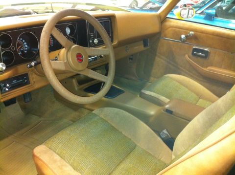 1976 Pontiac Trans Am - Interior view of a car with plaid seats and a tan dashboard, showing the steering wheel and gauges.