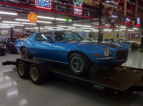 1976 Pontiac Trans Am - A blue muscle car from the 1970s is displayed on a trailer inside a showroom.