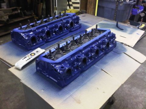 1979 Ford Bronco - A pair of blue engine cylinder heads sit on a table, with a remote control nearby.