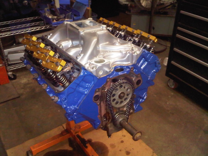 Ford blue V8 long block on an engine stand with aluminum intake and exposed timing chain